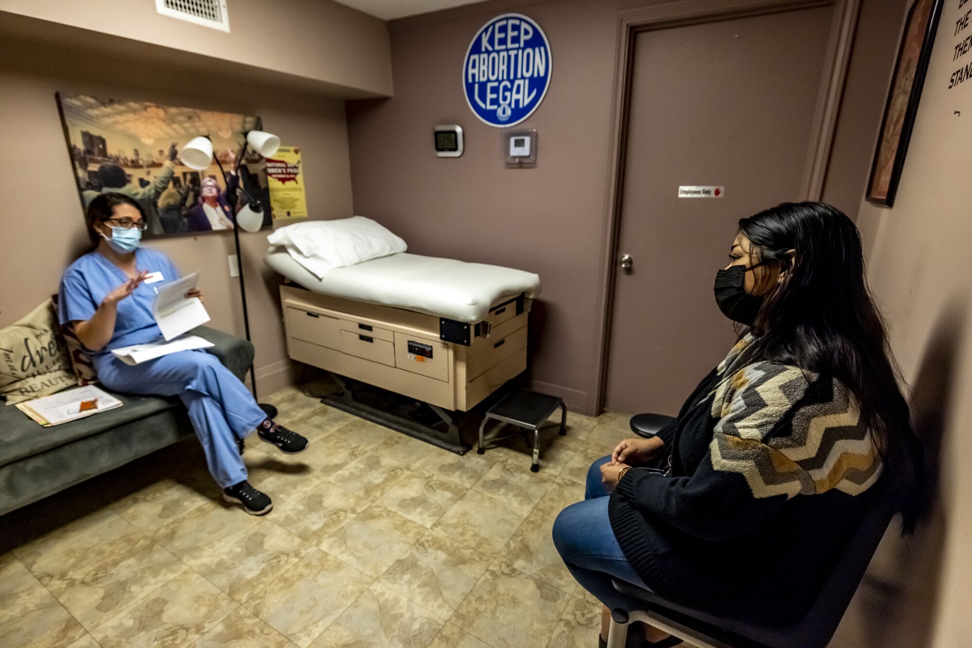 A female doctor, seated left, consults with a woman before she has a medication abortion.