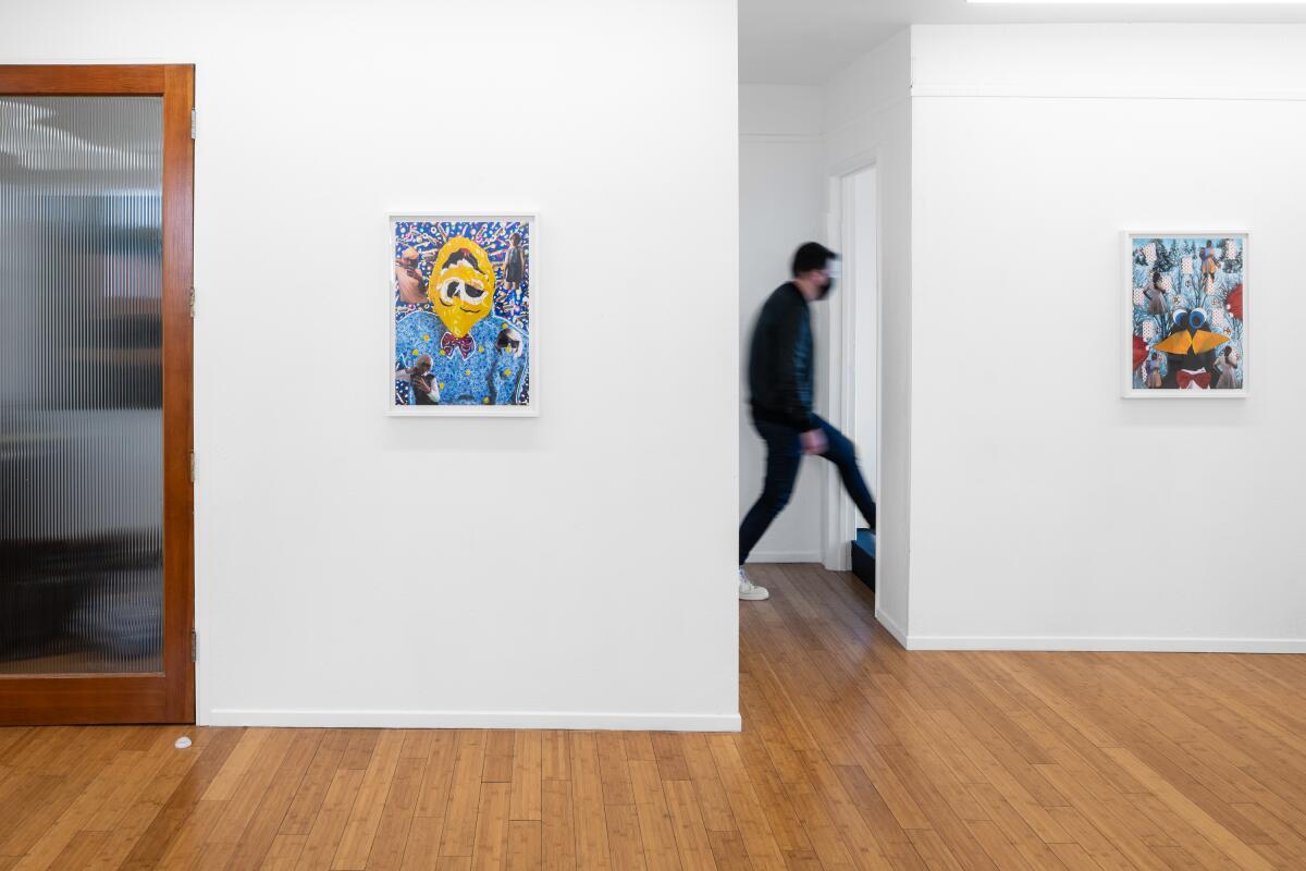 A man walks through the back of an art gallery with framed collages