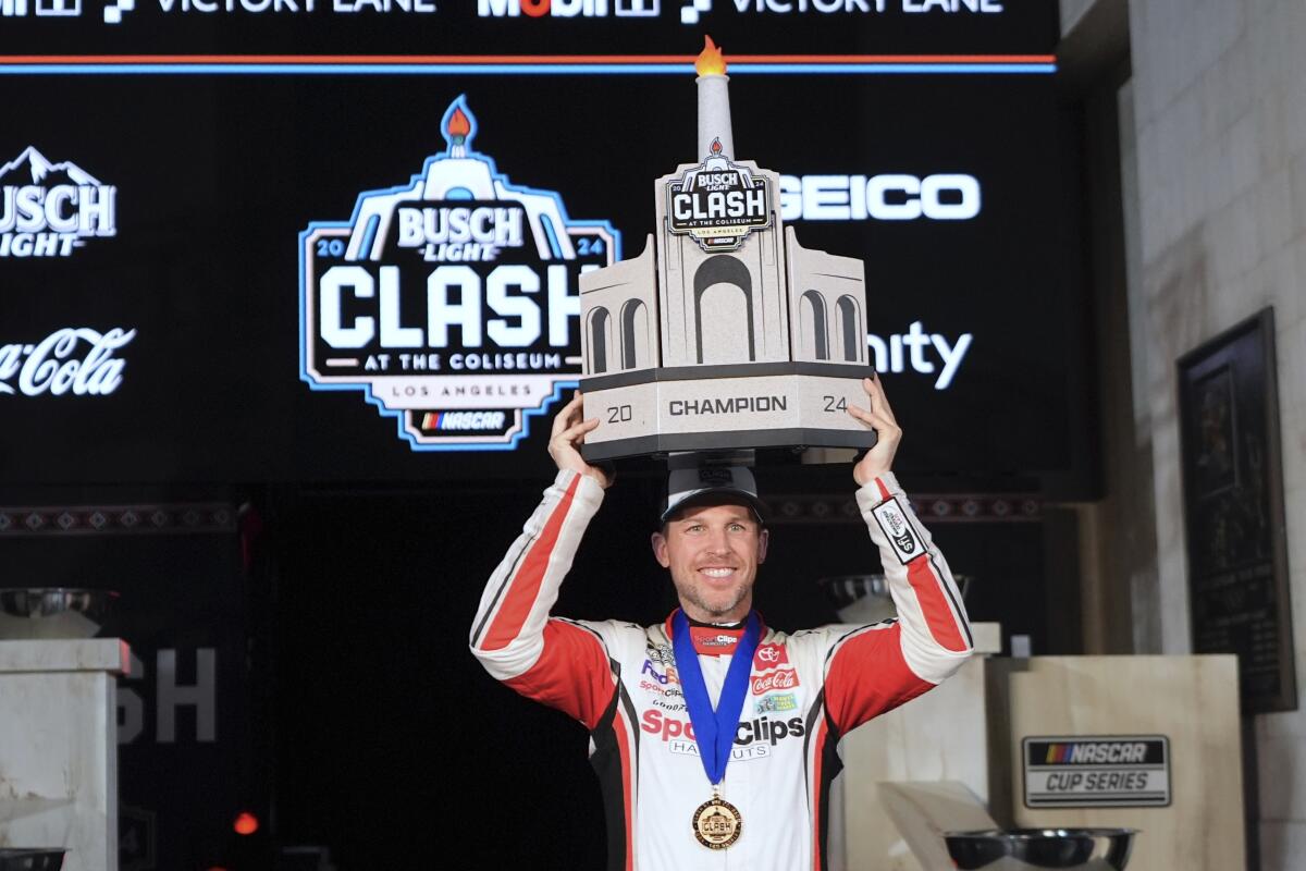 Denny Hamlin celebrates with the winner's trophy following his victory in the NASCAR Busch Light Clash at the Coliseum.