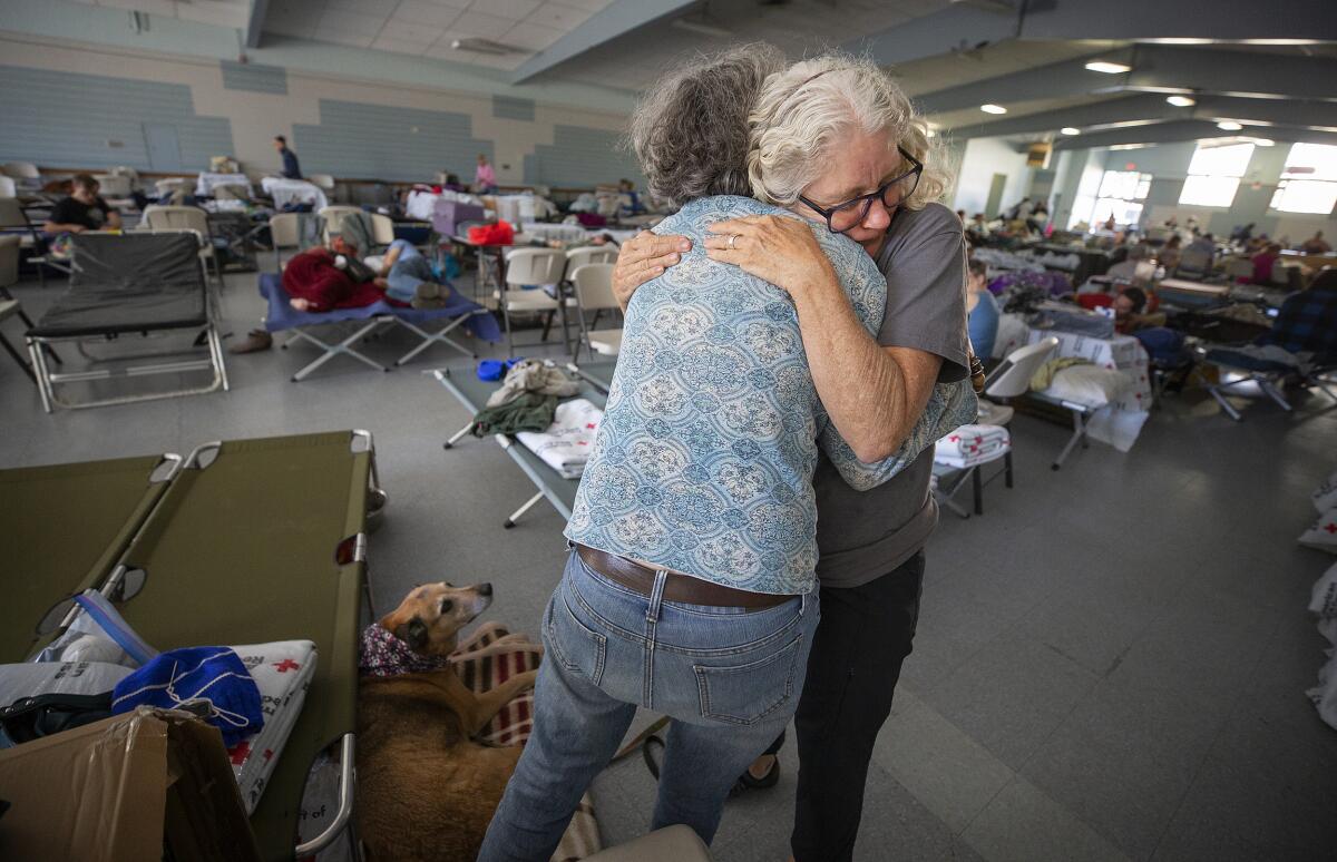 Volunteer Barbara Wood gives a hug to a Kincade fire evacuee at a Red Cross shelter at the Sonoma County Fairgrounds in Santa Rosa, Calif.