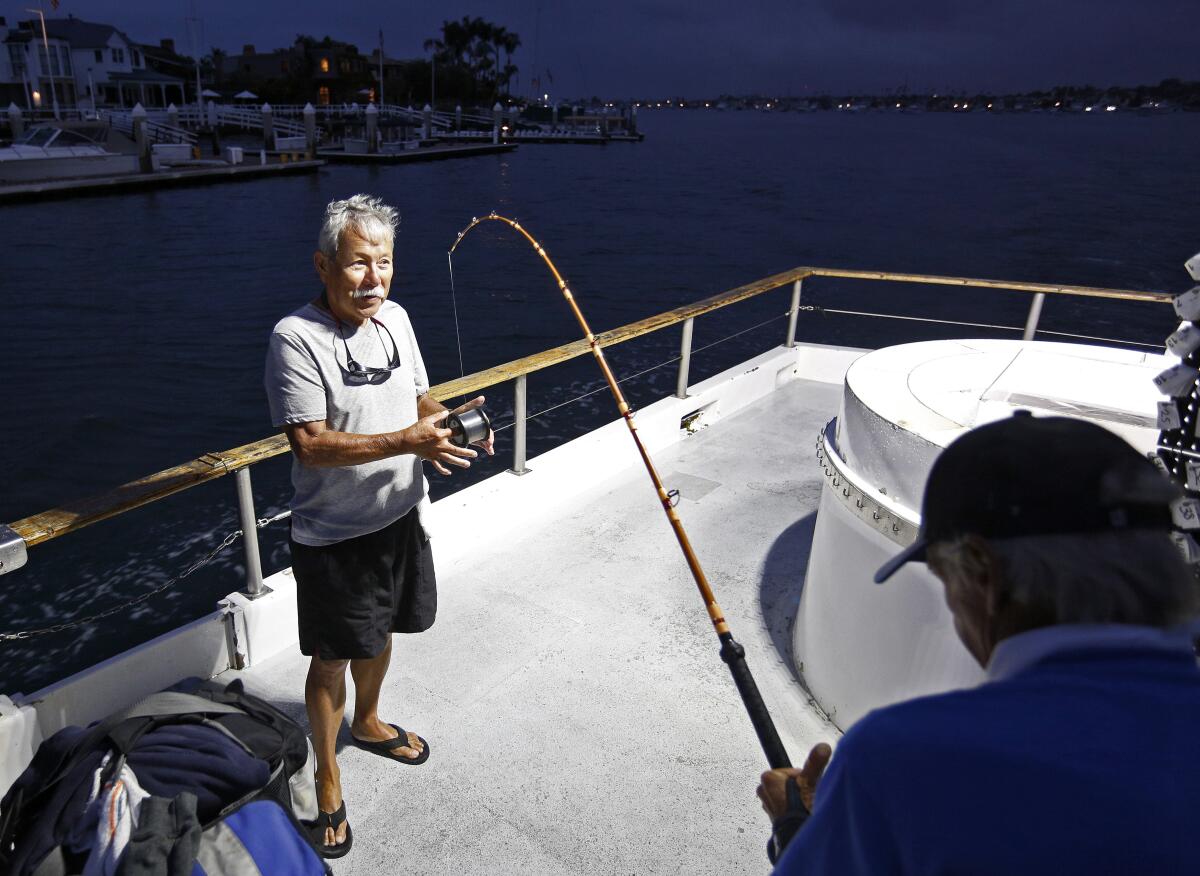 Arnold Kubo, 73, left, helps 71-year-old Don Frazier, both from Costa Mesa, load line onto his reel on Wednesday.