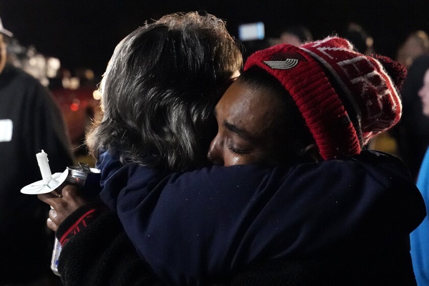 Jessaundra Jackson, right, an employee of Mayfield Consumer Products, hugs another person at the conclusion of a candlelight vigil in the aftermath of tornadoes that tore through the region several days earlier, in Mayfield, Ky., late Tuesday, Dec. 14, 2021. (AP Photo/Gerald Herbert)