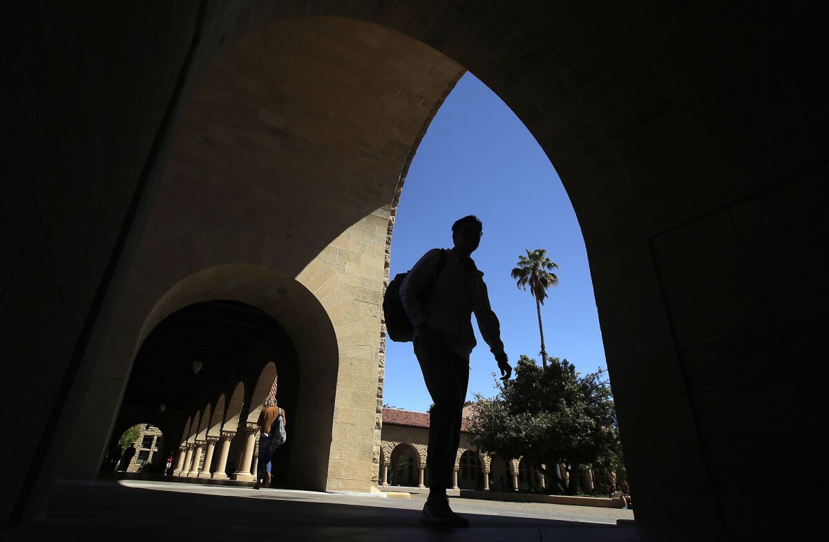 A silhouette of a person walking through an arched pathway of a stone building.