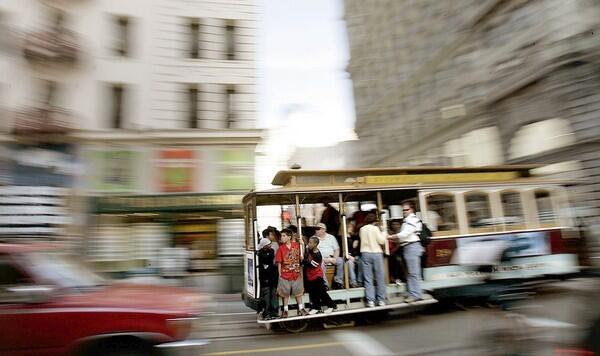 A loaded cable car moves through the heart of San Francisco.