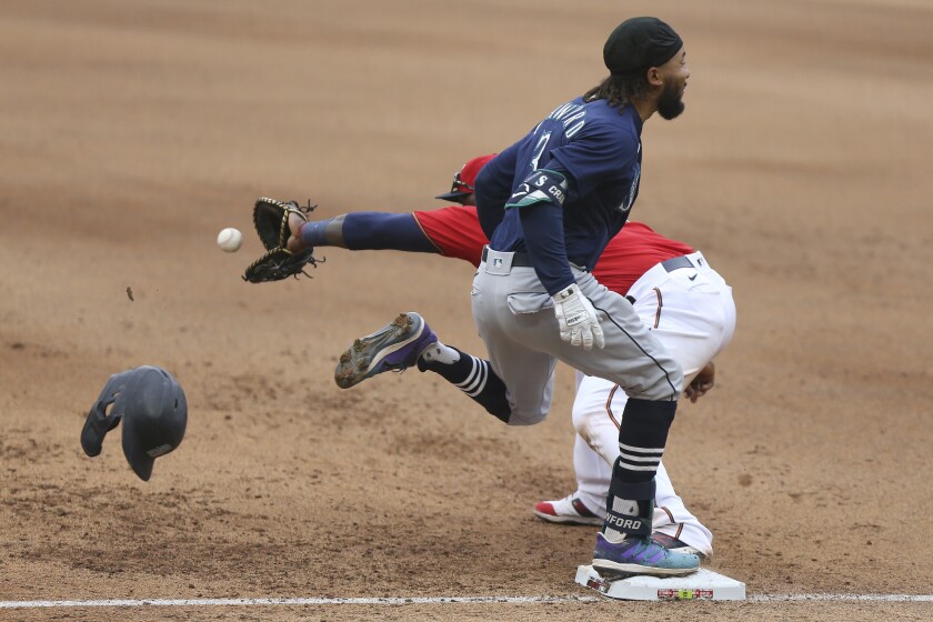 Seattle Mariners' J.P. Crawford (3) best the throw to first base as Minnesota Twins' Miguel Sano (22) reaches for he ball during the eighth inning of a baseball game, Saturday, April 10, 2021, in Minneapolis. Seattle won 4-3 in the 10 innings. (AP Photo/Stacy Bengs)
