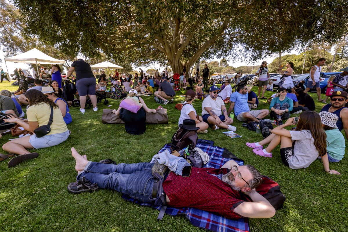 Thomas Sternsdorf, front, relaxes on a blanket as he and other people take advantage of the tree's shade during EarthFest.