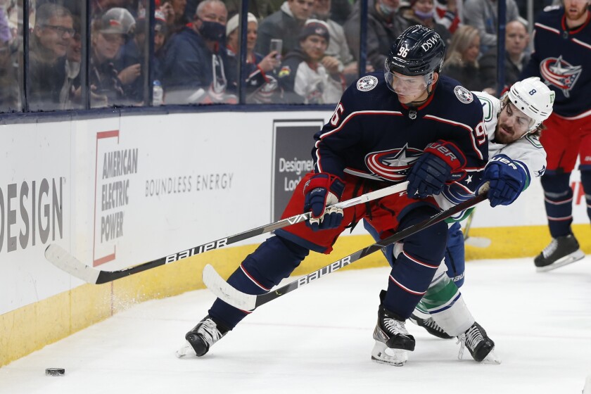 Columbus Blue Jackets' Jack Roslovic, left, and Vancouver Canucks' Conor Garland chase a loose puck during the first period of an NHL hockey game Friday, Nov. 26, 2021, in Columbus, Ohio. (AP Photo/Jay LaPrete)
