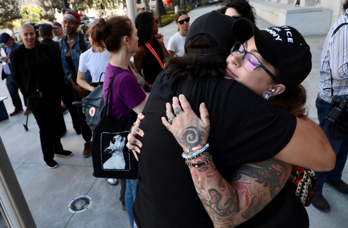 Anita Joy, right, who was with Johnny Factor when he was shot, hugs Gary Hoiness after the press conference.