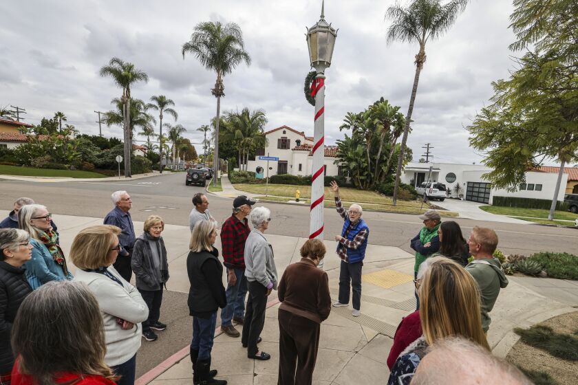 San Diego, CA - December 01: Kensington resident Jim Kelley-Markham (blue vest right of street light) talks to other area residents about his efforts to save the historic antique street lights in the neighborhood at the corner of Marlborough Drive and Middlesex Drive on Thursday, Dec. 1, 2022 in San Diego, CA. (Eduardo Contreras / The San Diego Union-Tribune)