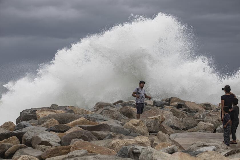 A tourist poses for a photo in front breaking waves before the expected arrival of Hurricane Lorena, in Los Cabos, Mexico, Friday, Sept. 20, 2019. Hurricane Lorena neared Mexico's resort-studded Los Cabos area Friday as owners pulled their boats from the water, tourists hunkered down in hotels, and police and soldiers went through low-lying, low-income neighborhoods urging people to evacuate. (AP Photo/Fernando Castillo)