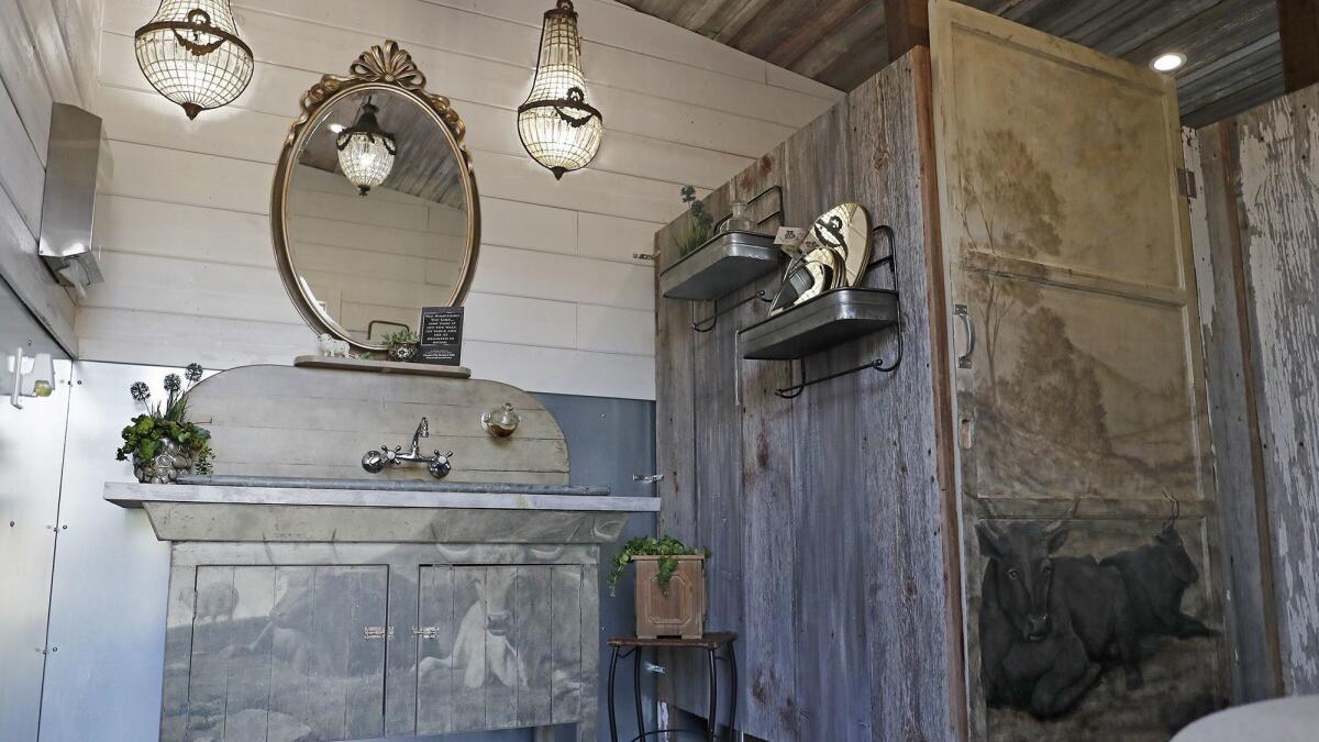 Anne Manassero designed the Manassero Farms women’s restroom with French antique chandelier sconces and 100-year-old wooden barn doors that she had custom-painted.
