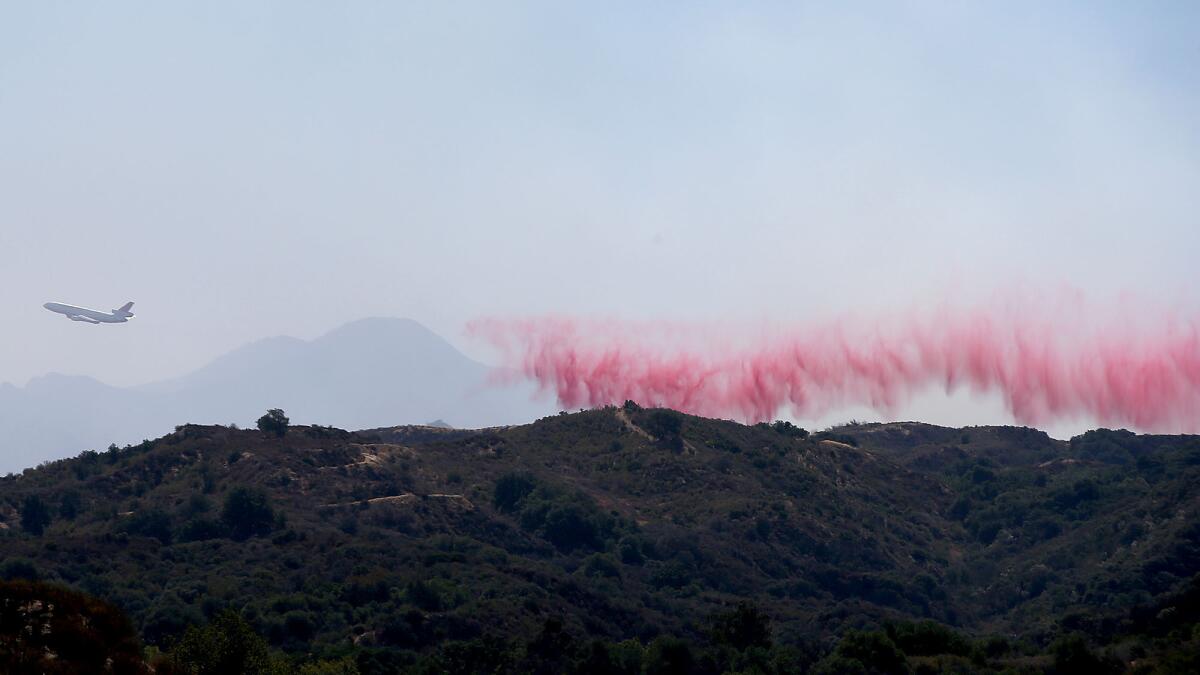 A firefighting jumbo jet paints a ridge with fire retardant near Santa Clarita on Sunday.