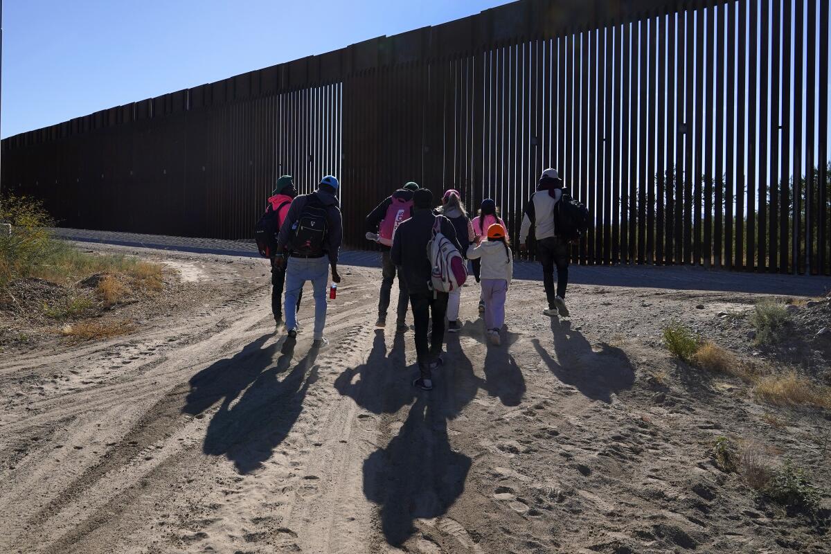 ARCHIVO - Un grupo de migrantes camina a lo largo de la frontera 