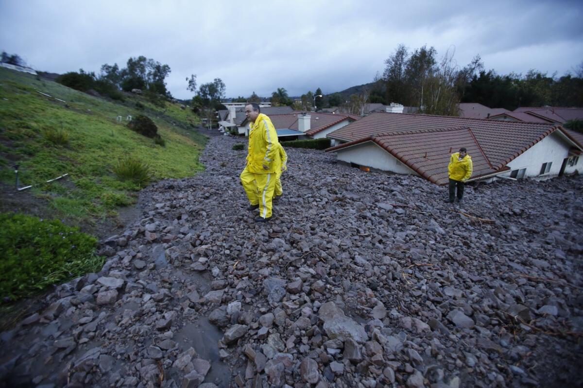 Ventura County sheriff's deputies climb the cascade of mud and rock that filled the backyards of homes along San Como Lane in Camarillo Springs on Friday morning.