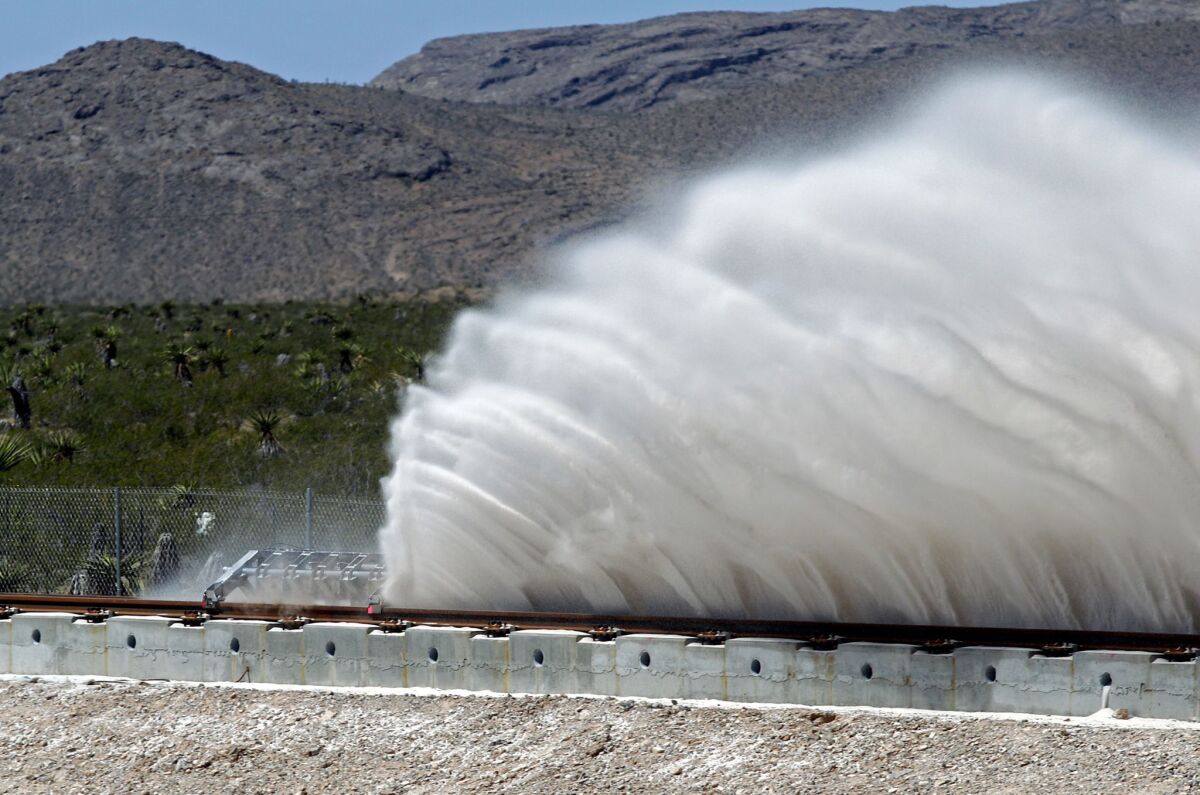 Sand rises from a track as a test carrier is slowed during the first test of the propulsion system at the Hyperloop One test site Wednesday in Las Vegas.