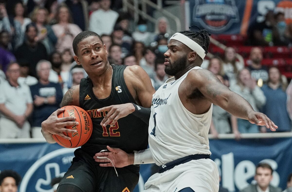Winthrop forward Cory Hightower (12) drives into the defense of Longwood guard Isaiah Wilkins (1) during the first half of an NCAA college basketball game for the championship of the Big South Conference men's tournament on Sunday, March 6, 2022, in Charlotte, N.C. (AP Photo/Rusty Jones)