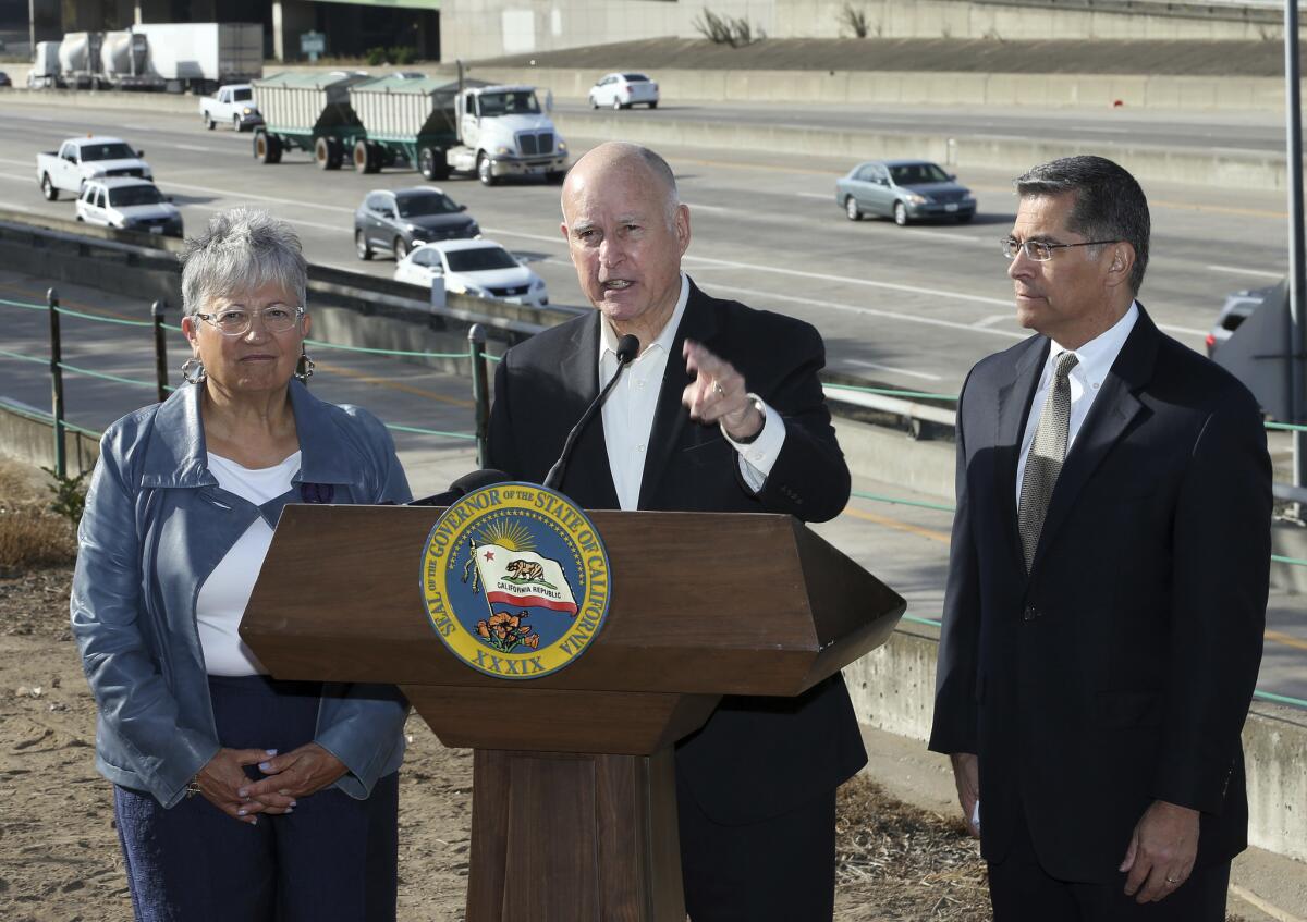 Then-Gov. Jerry Brown, center, blasts a Trump administration plan to roll back vehicle emissions standards in 2018. Brown is flanked by California Air Resources Board Chair Mary Nichols and Atty. Gen. Xavier Becerra.