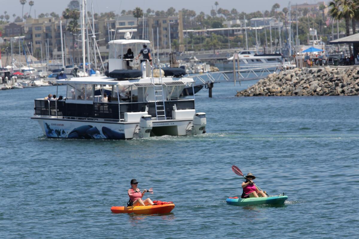 Kayakers share the Oceanside Harbor with larger boats in July 2020.