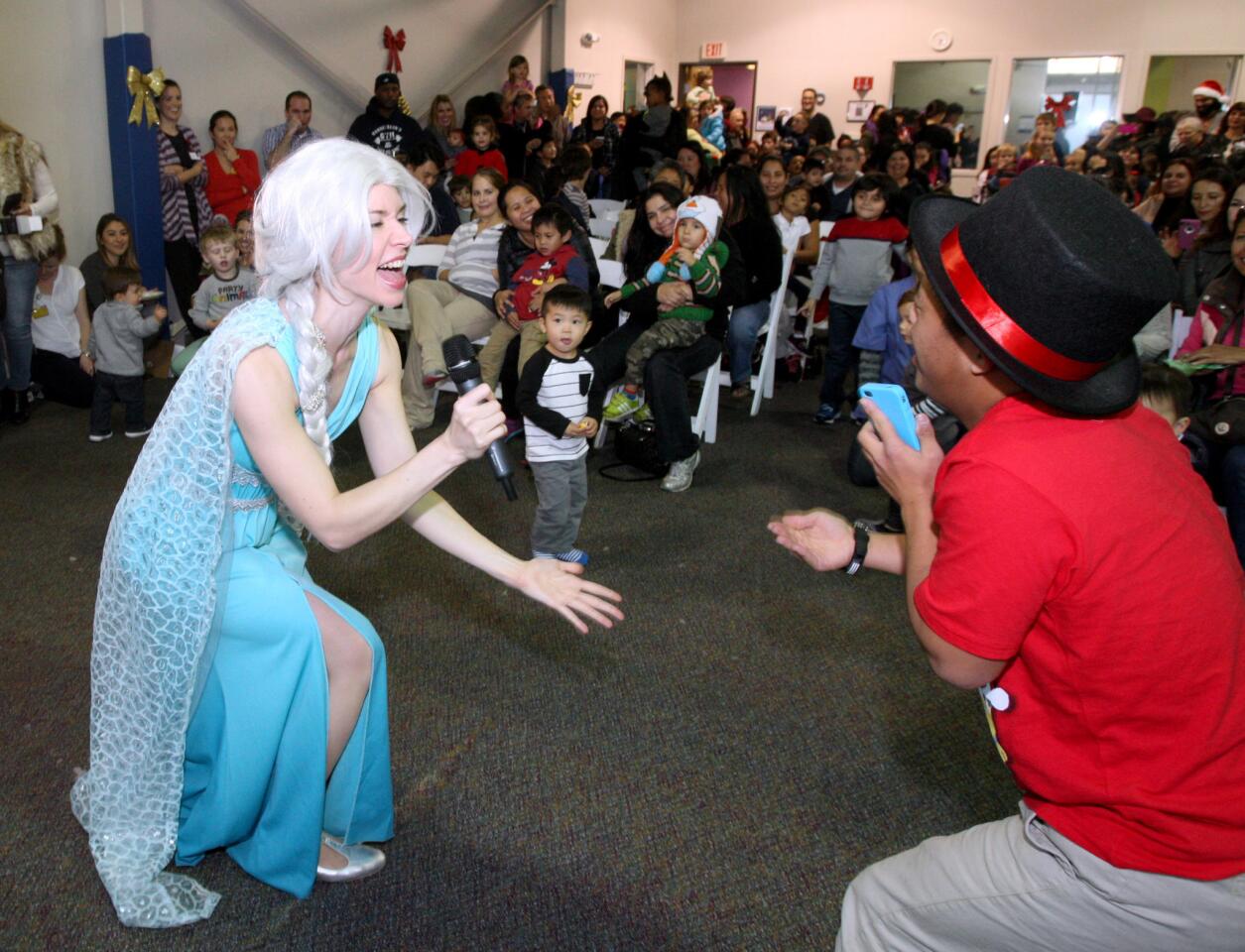 As 20-yr. old J.C. Asprer, of Glendale, sings along, right, the character Elsa sang a song for the children attending the Glendale Adventist Medical Center-sponsored Christmas party at the Play to Learn Center in Eagle Rock on Tuesday, December 15, 2015.