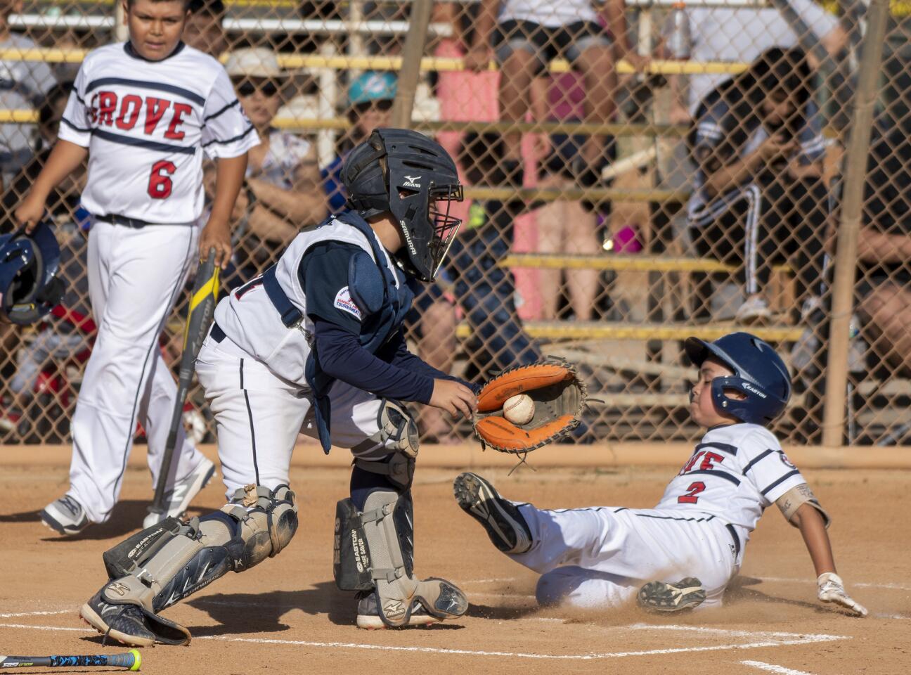 Newport Harbor Baseball Association's Brooks Francis attempts to make a tag on Garden Grove's Khai Anderson during a PONY Mustang 10-and-under district tournament game at Fountain Valley Sports Park.