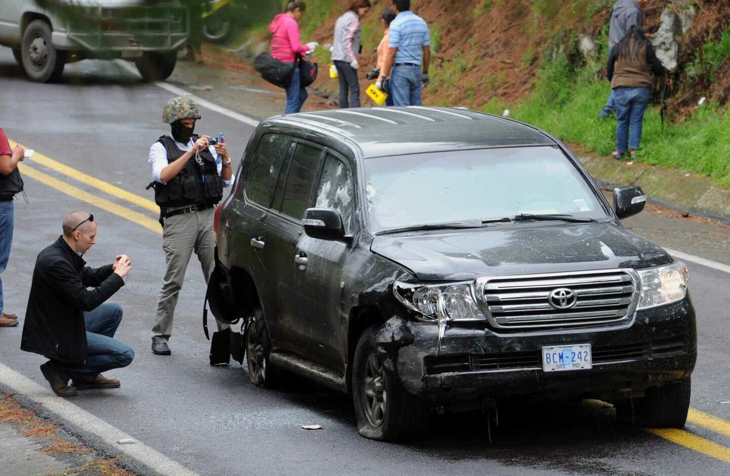 Forensic investigators take photos of a U.S. diplomatic vehicle on which federal police opened fire Friday south of Mexico City. The shooting left two embassy staffers wounded.