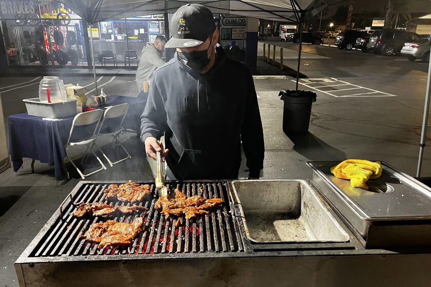 Hector "Guero" Garcia grills carne asada over a charcoal grill at Taqueria El Puerto in Anaheim.