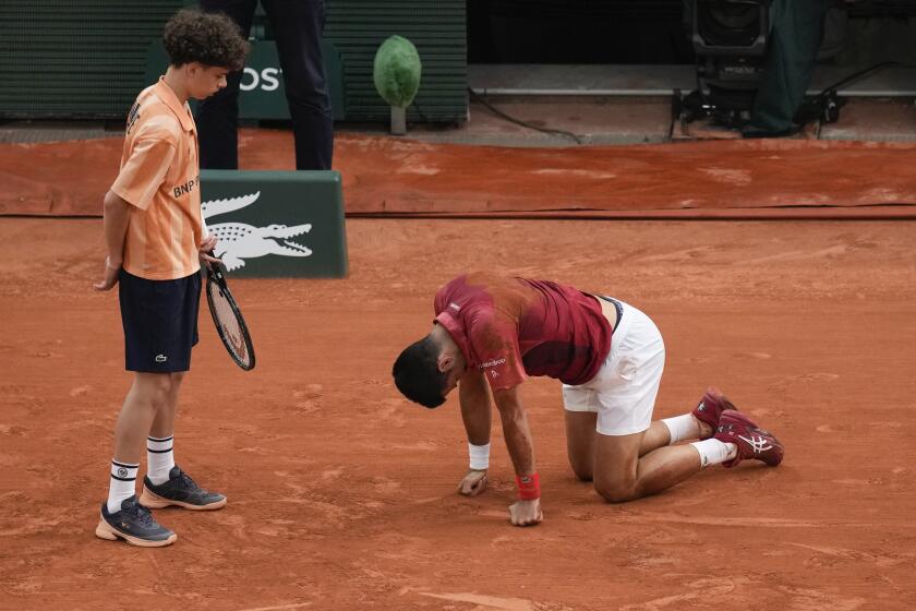 Un recogepelotas auxilia a Novak Djokovic tras sufrir una caída durante el partido de cuarta ronda contra Francisco Cerúndolo en el Abierto de Francia, el lunes 3 de junio de 2024, en París. (AP Foto/Christophe Ena)