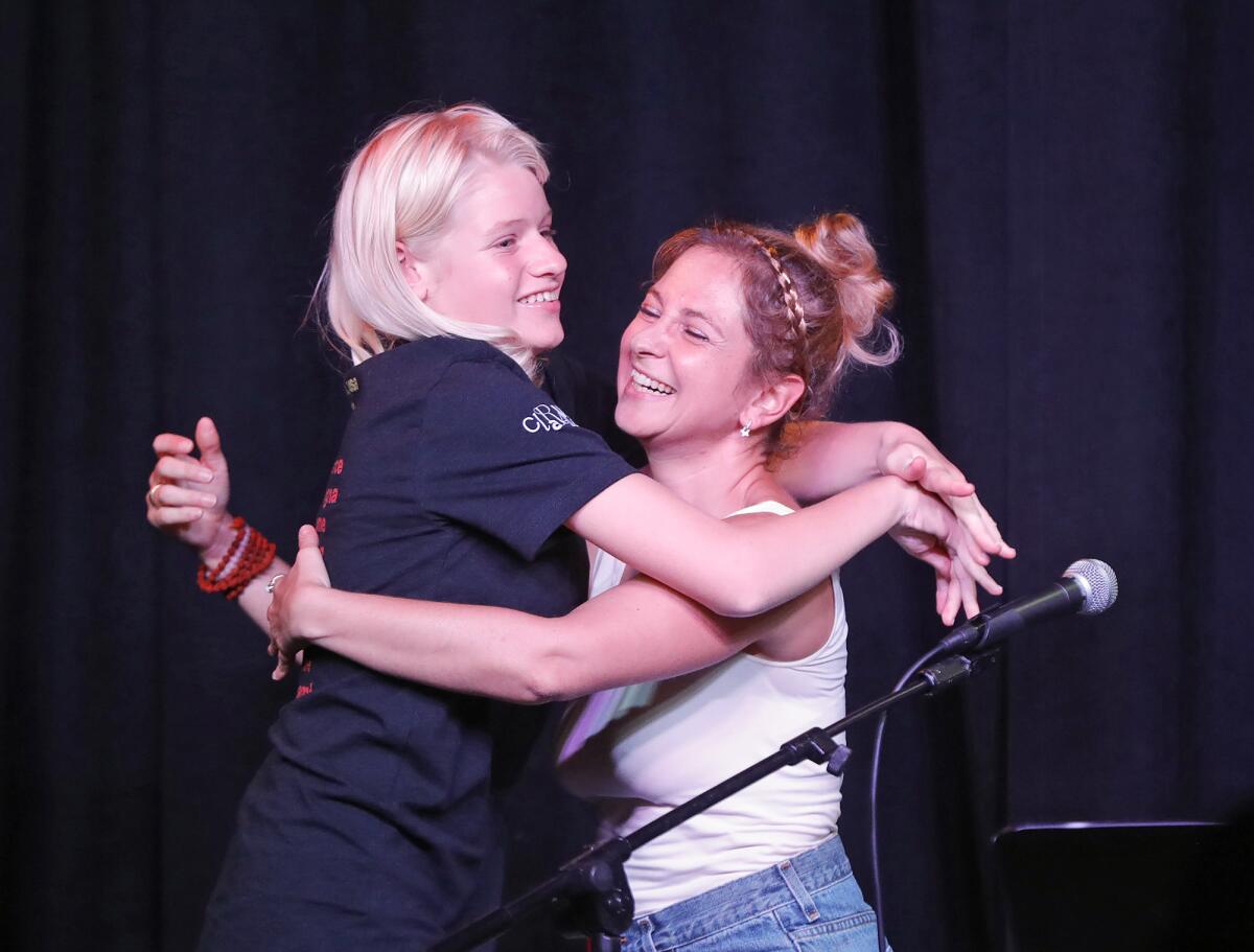 Actor and art therapist Lavinia Constantino, right, embraces 16-year-old Clara Woods, after performing in "Painted Words."