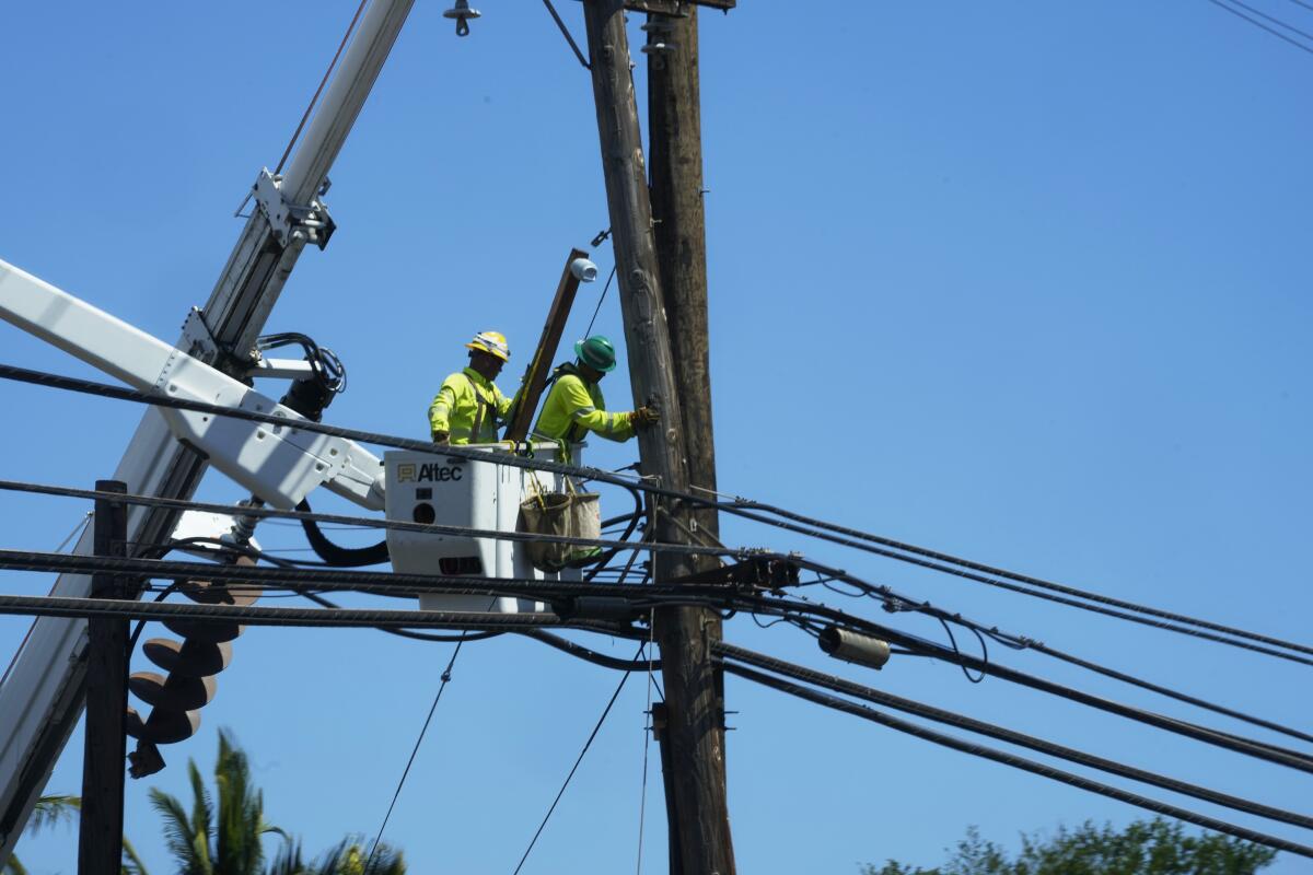 ARCHIVO - Linieros trabajan en postes eléctricos el 13 de agosto de 2023, en Lahaina, Hawai, 