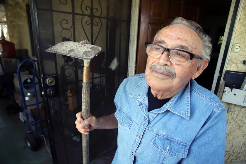 Fausto Rios, 82, of Colton, who worked as a "bracero" or farm worker for most of his life, poses with a type of hoe a farm worker would use, he pose for a picture at his home in Colton on Monday, June 13, 2022. Rios now wants to play a role in exposing and ending the long history of the mistreatment of hispanic farm workers.