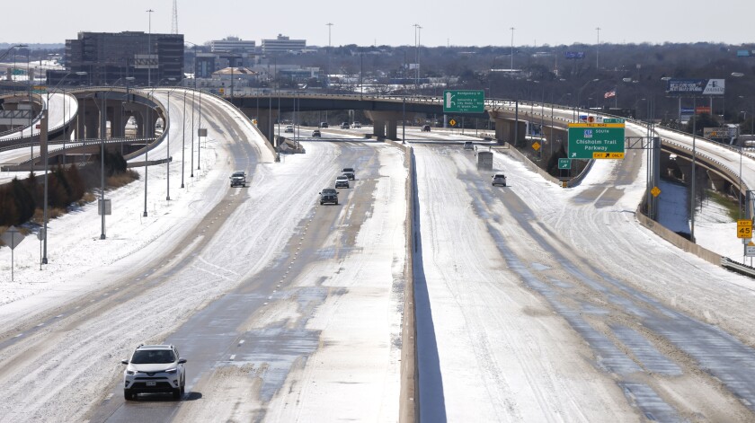 A snow-covered freeway with very few vehicles