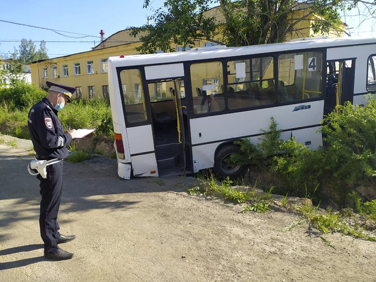 In this photo provided by Russian Interior Ministry, a Russian police officer stands near the bus which crashed into a bus stop in the town of Lesnoy about 1,350 kilometers (840 miles) east of Moscow, Russia, Thursday, June 10, 2021. A bus crashed into a bus stop in Russia's Sverdlovsk region on Thursday morning, killing six people and injuring 15 others, local officials said. The bus was carrying workers to a plant in the town of Lesnoy about 1,350 kilometers (840 miles) east of Moscow. (Russian Interior Ministry via AP)