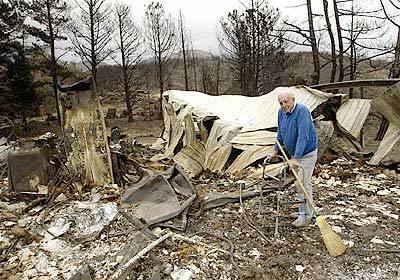 "All that I own is gone," said Clifford Clark, 75, standing in the rubble of his home in Waterman Canyon. Clark, a resident of the San Bernardino Mountains since 1967, lost 35 vintage English motorcycles in the fire. "I'm upset, but I'm not going to wimpy cry about it," he said.
