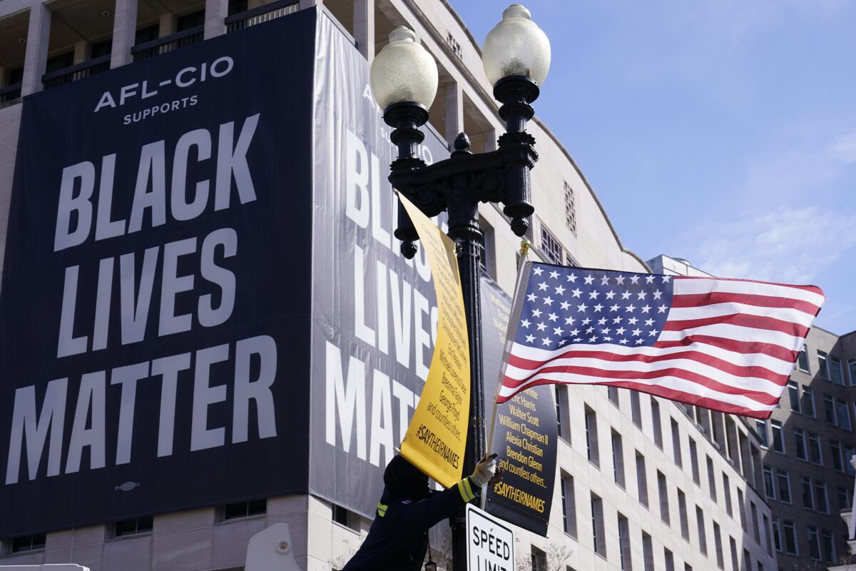 A U.S. flag flies by a banner reading "AFL-CIO Supports Black Lives Matter"