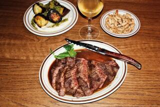 Steak, roasted sweet potatoes and marcona almonds with a glass of white wine on a wood table at Sam's Place in Highland Park