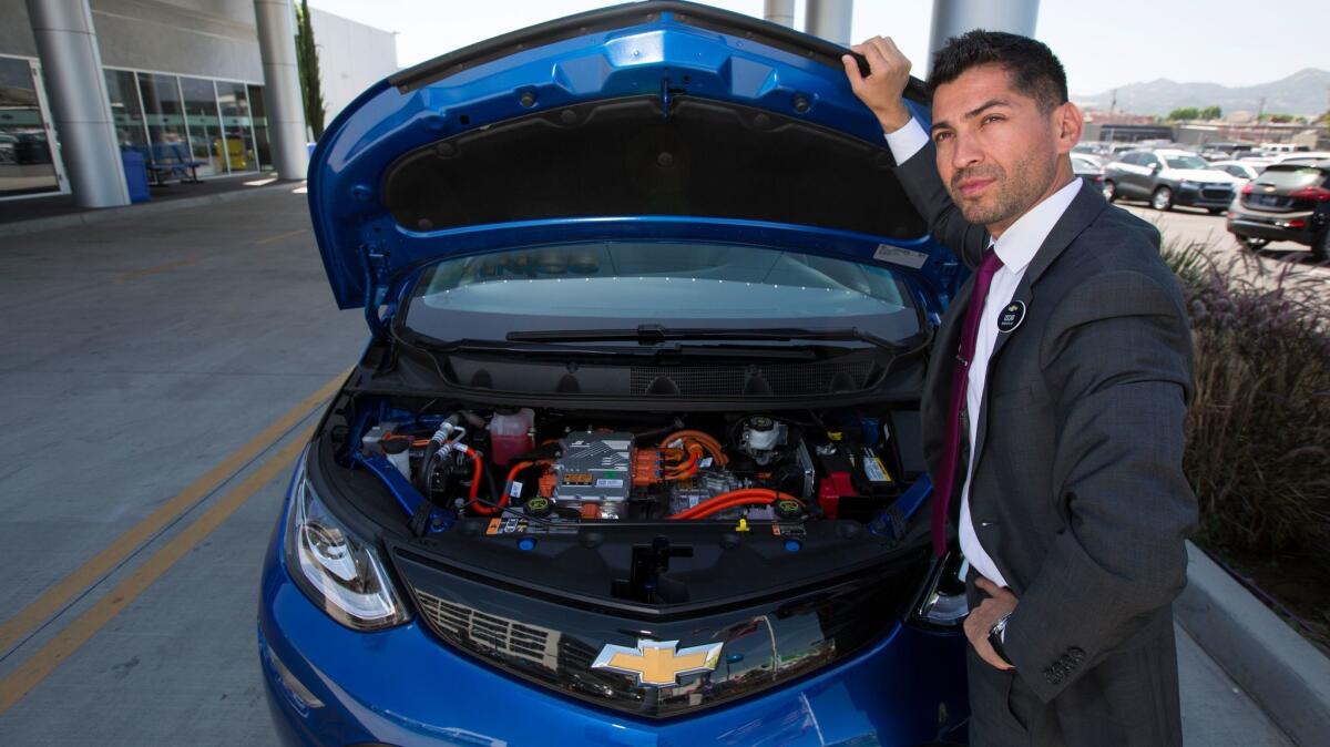 Community Chevrolet sales manager Oscar Gutierrez with a Bolt EV electric car in Burbank.