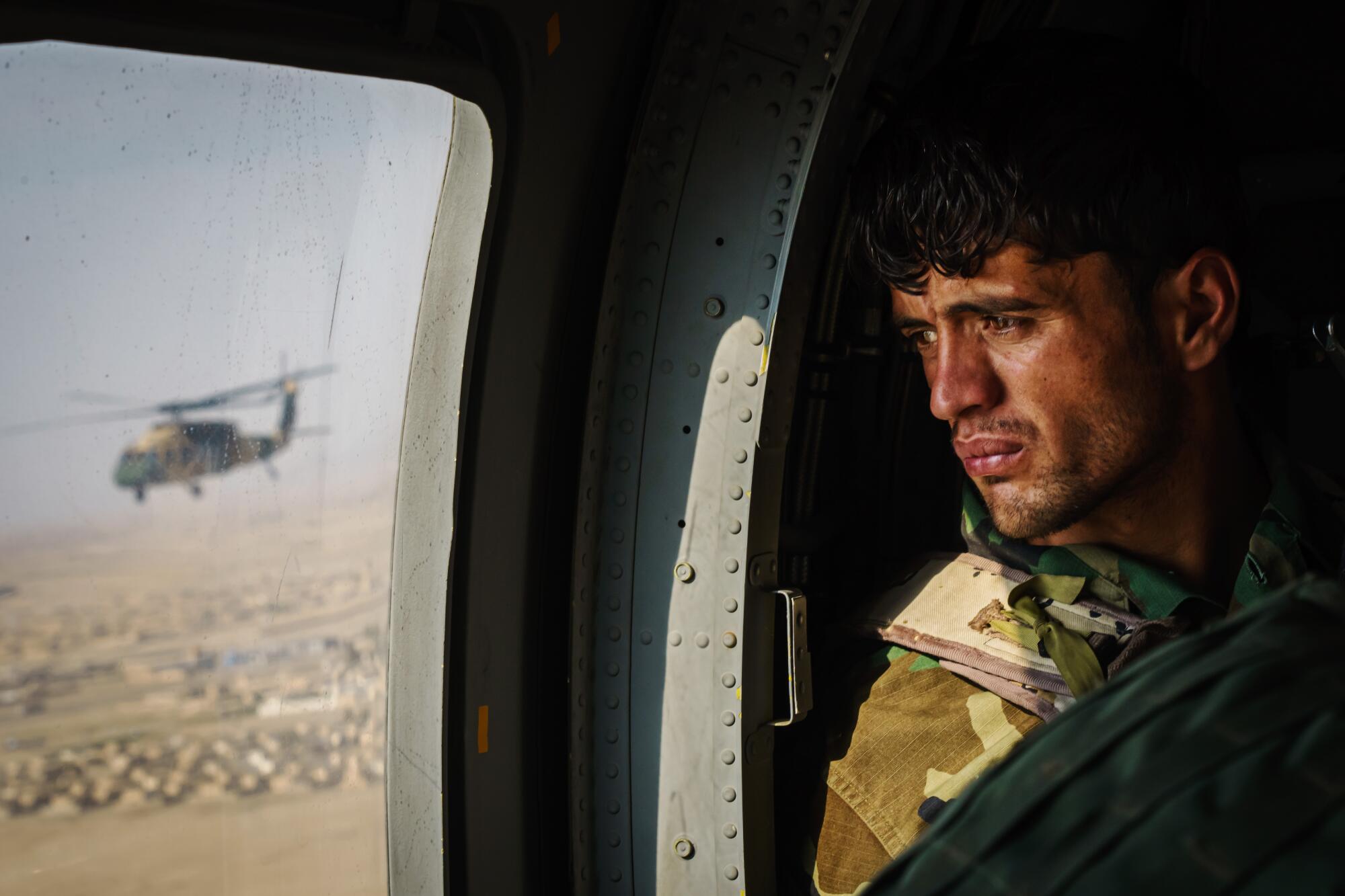 A soldier surveys the terrain out the window during a resupply flight on a UH-60 Black Hawk 