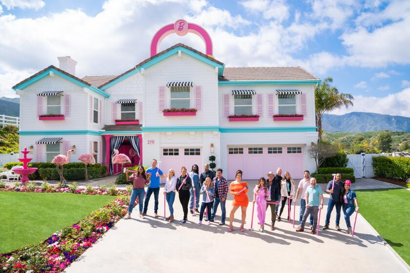 A real-life Barbie Dream House: a white house with turquoise trim, pink shutters, black and white awnings and a pink fountain 