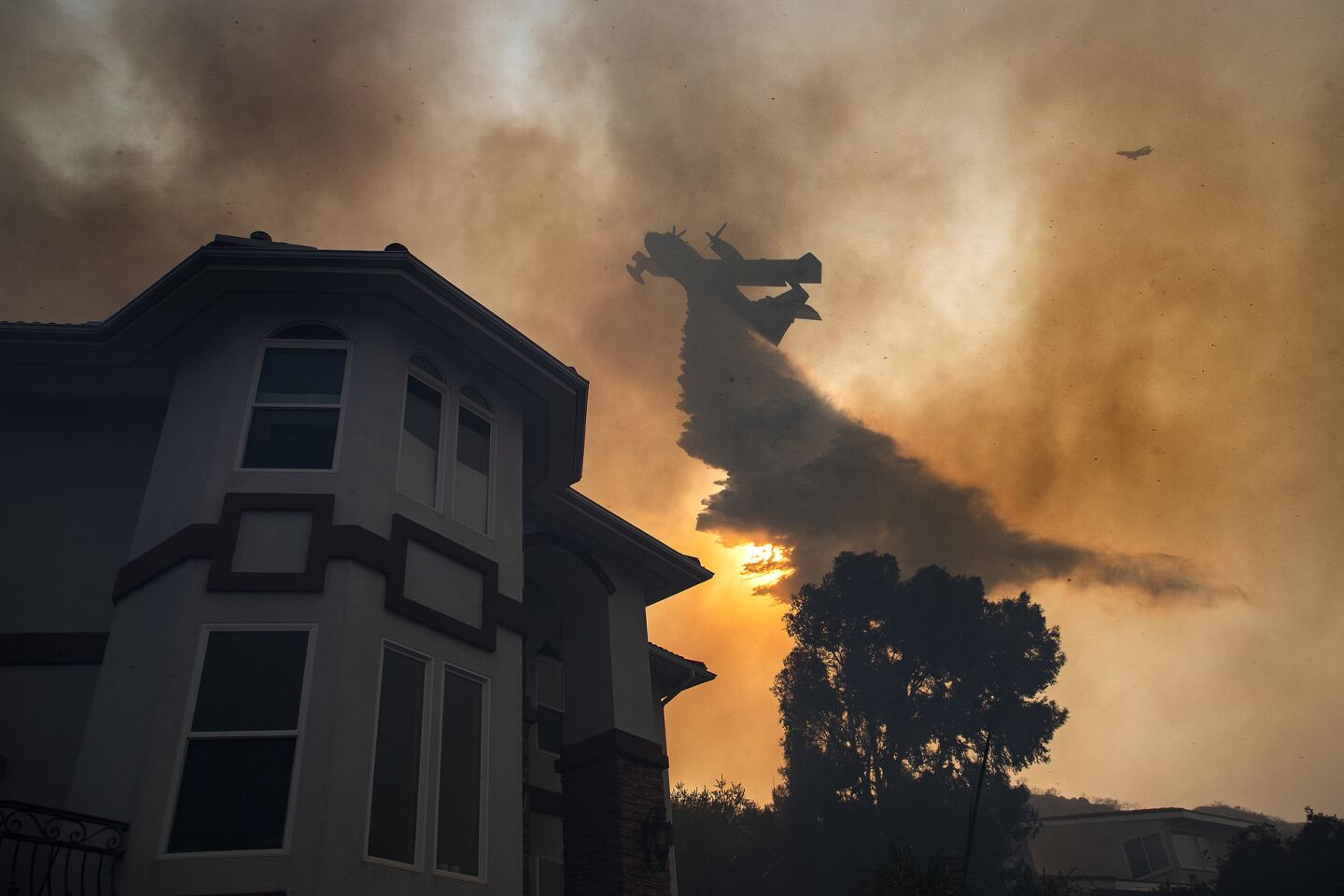 An air tanker drops a load of water to save a home in Lake Elsinore, Calif.