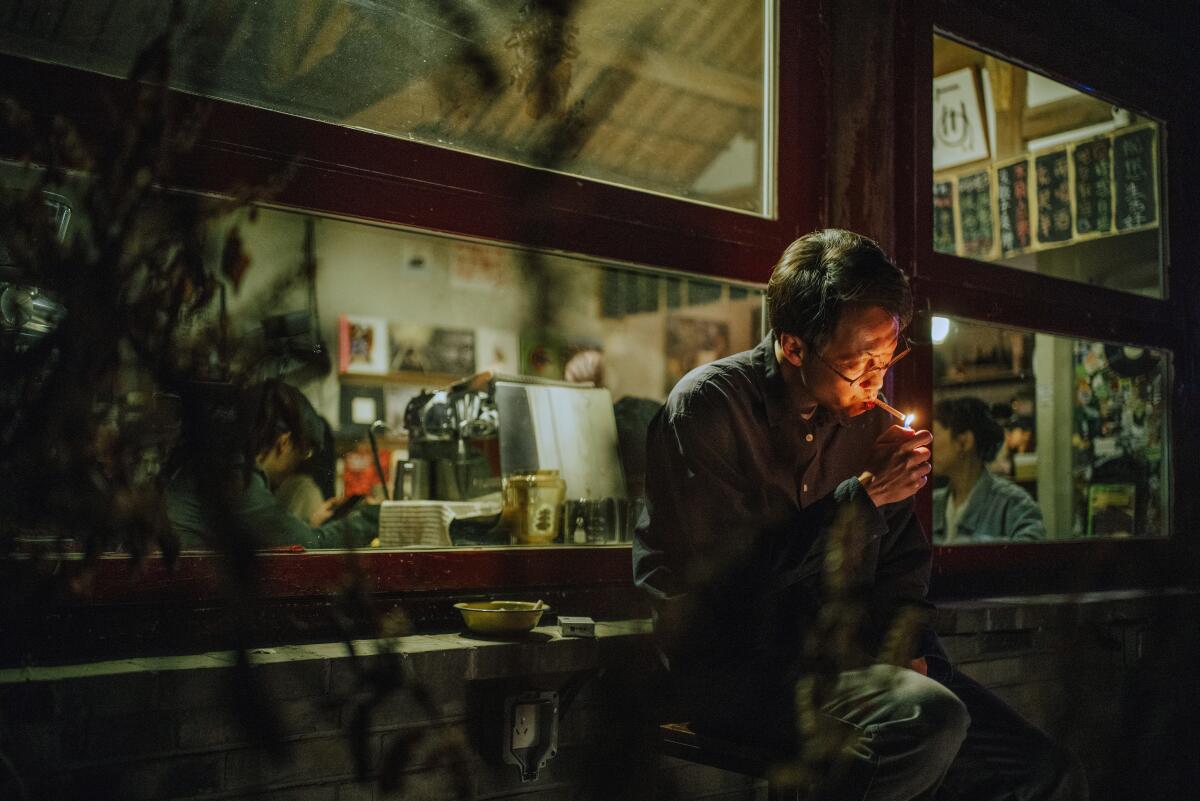 A man lights a cigarette in his apartment.