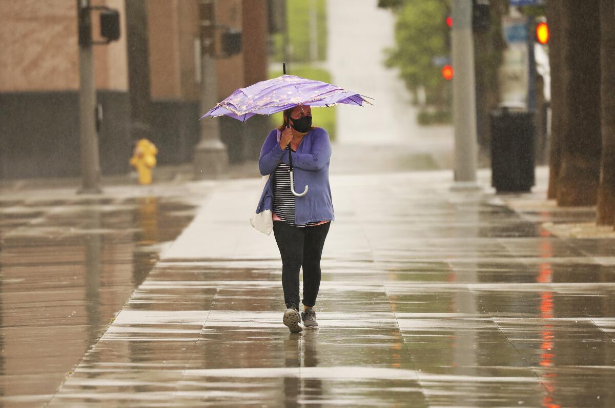 Blanca Torres walks in the rain in downtown Los Angeles in May.