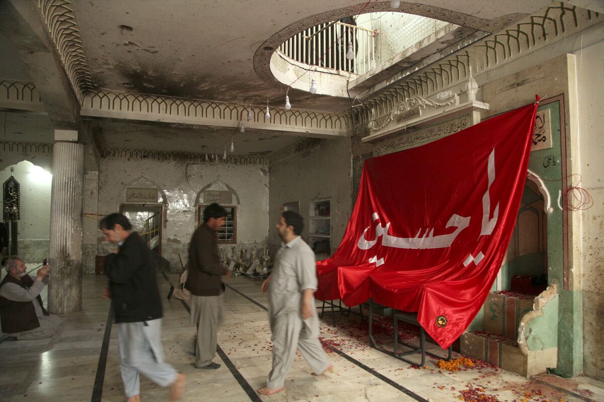 People visit Kusha Kisaldar Shiite Mosque, the site of March 4 suicide bombing, to offer prays for bombing victims, in Peshawar, Pakistan, Wednesday, March 9, 2022. In northwest Pakistan the remains of an IS suicide bomber are still visible on the once ornate walls of a mosque where last month more than 63 worshippers died as they knelt in prayer. The bomber, an Afghan identified by IS as Julaybib al-Kabuli, was from the capital Kabul. (AP Photo/Muhammad Sajjad)