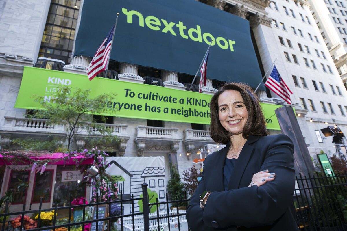 A woman stands before the New York Stock Exchange building with Nextdoor banners hanging on it. 