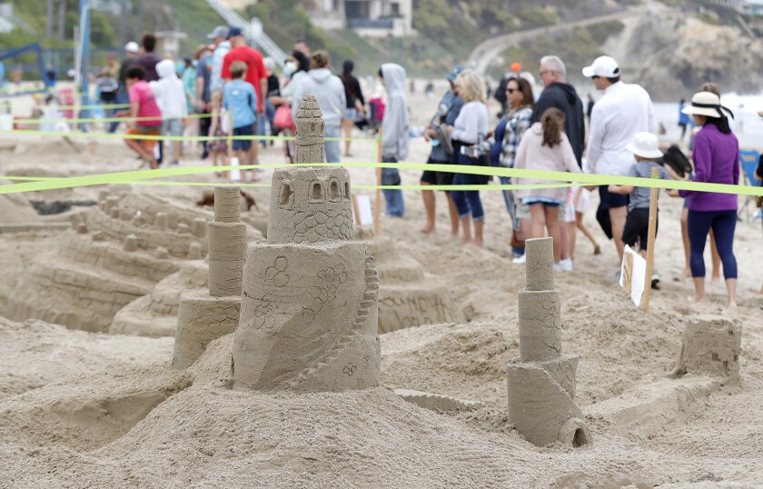 A crowd lines the path in front of the Newport Beach 59th annual sandcastle contest entries at Corona del Mar State Beach.