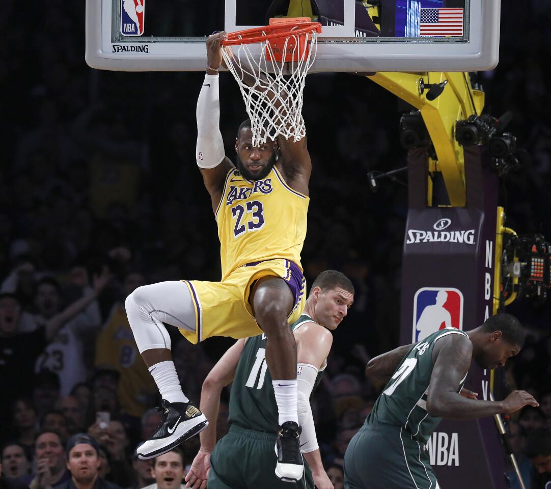 LeBron James hangs from the rim after a dunk during the first half of a game against the Bucks on March 6 at Staples Center.