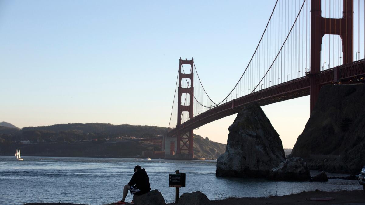 A man sits on a rock overlooking the Golden Gate Bridge on Nov. 11, 2015.