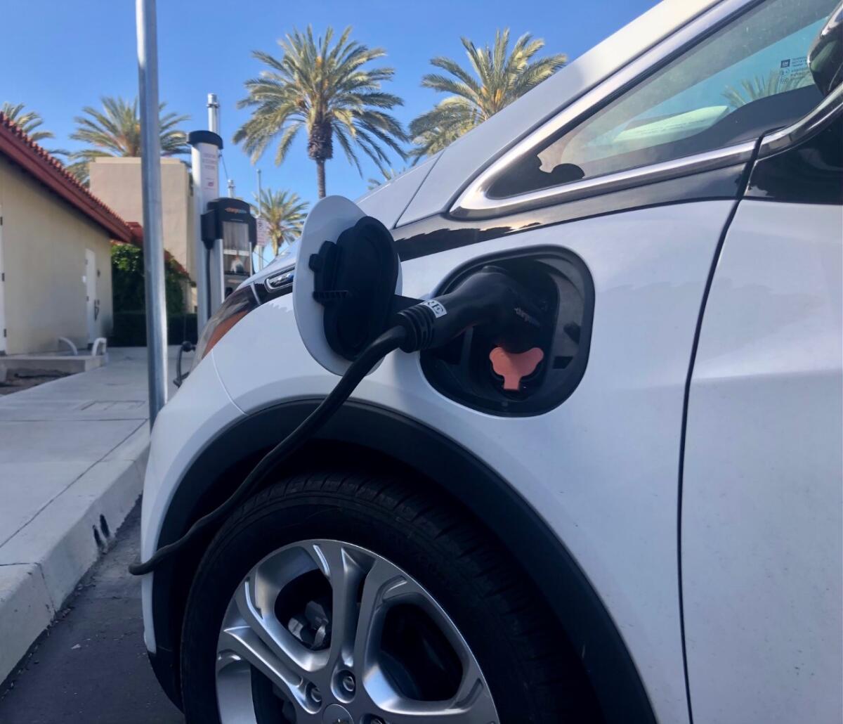 A cord is plugged into a car outdoors.