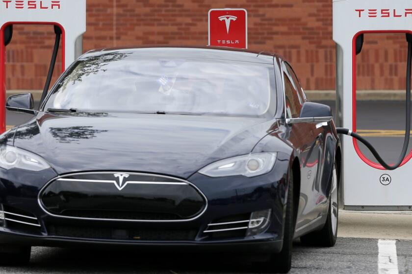FILE - In this Saturday, June 24, 2017, file photo, a Tesla car recharges at a charging station at Cochran Commons shopping center in Charlotte, N.C. On Monday, Sept. 11, 2017, Tesla Inc. announced that more charging stations are on the way. The stations will be installed at places such as supermarkets and shopping centers, and in cities like Chicago and Boston. (AP Photo/Chuck Burton, File)