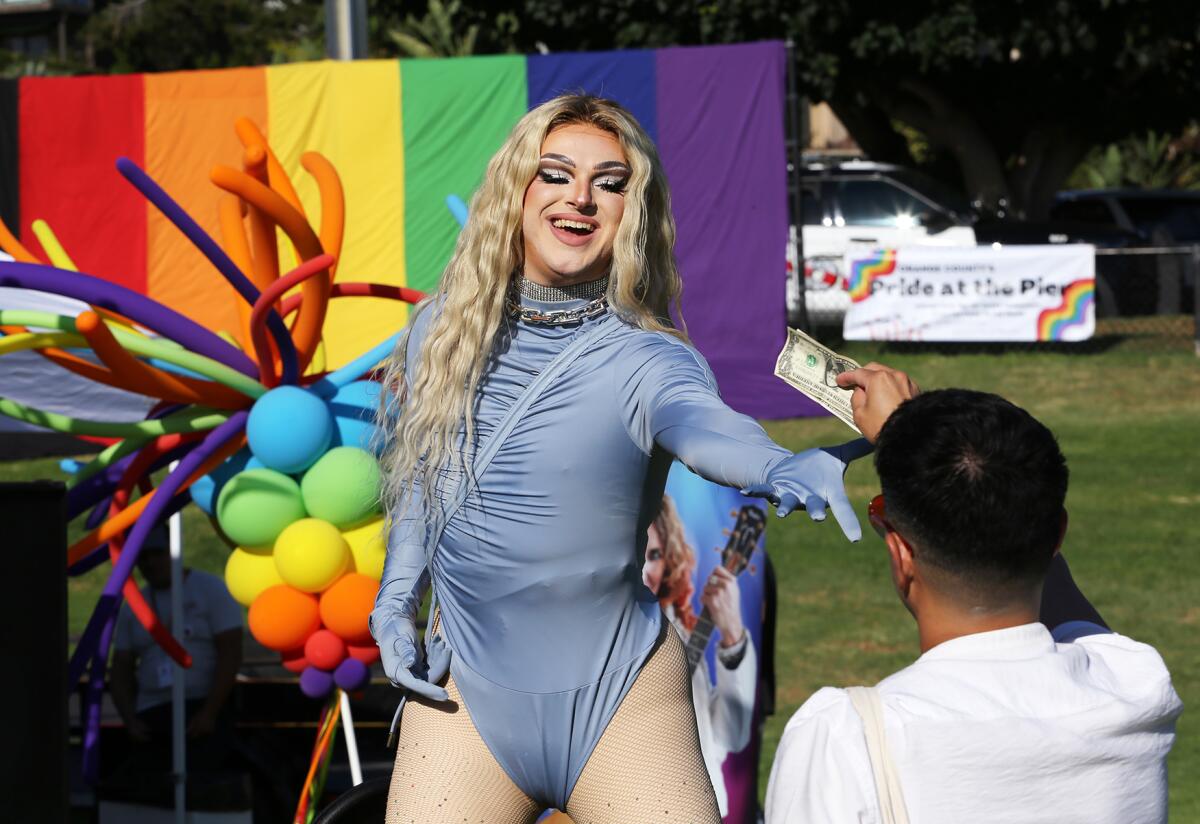 Drag queen Cucu Chanel gets a tip as she performs during the Laguna Beach Pride Festival at Lang Park on Saturday.