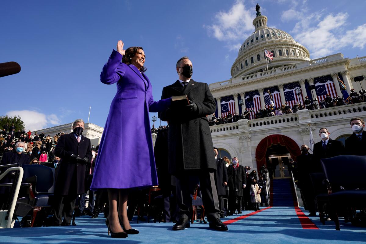 Kamala Harris, in a purple coat, raises her right hand as she's sworn in as vice president.